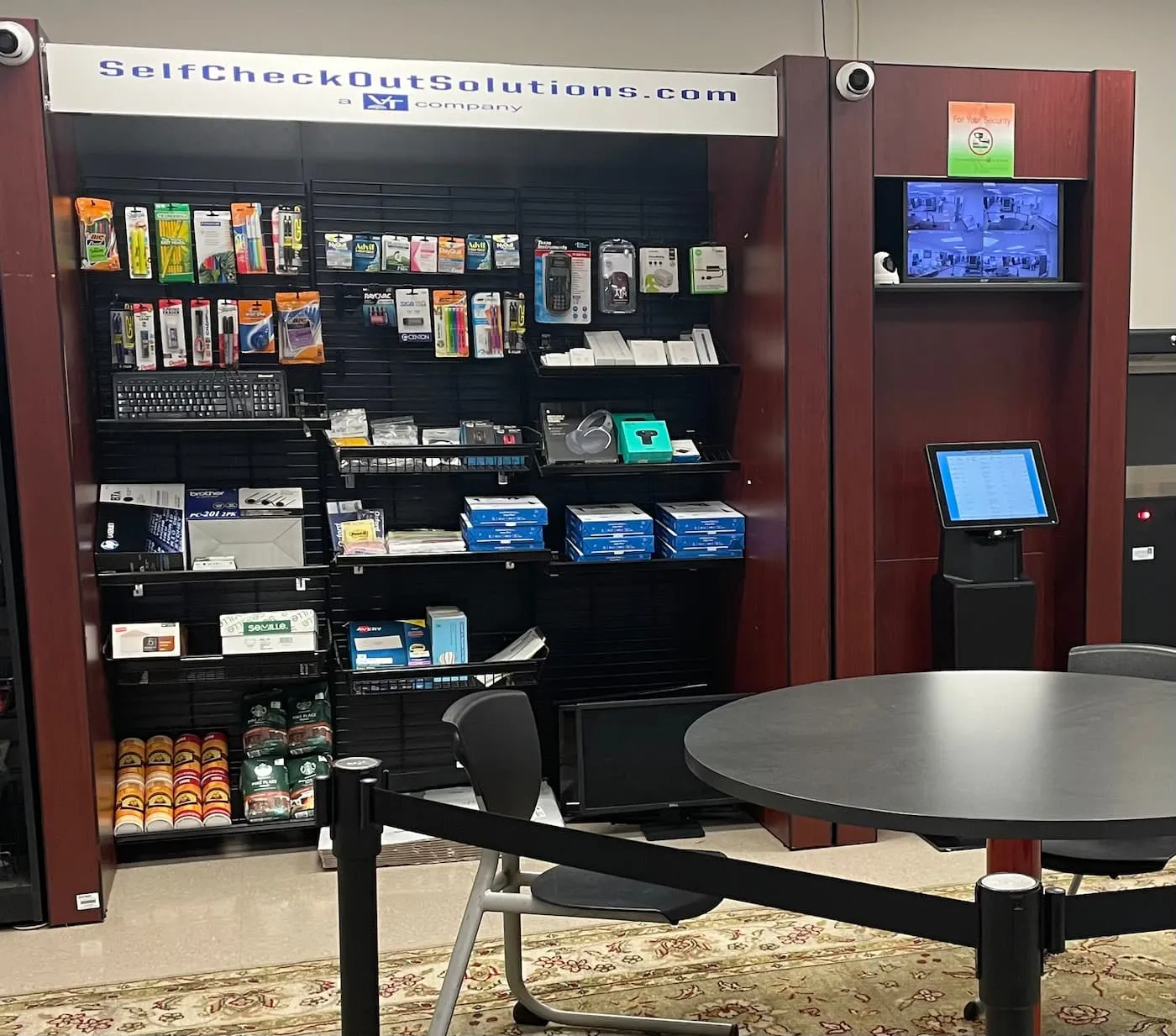 A self-checkout station in a break room with a laptop and a coffee cup on the table.